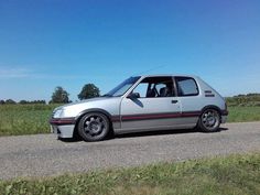 a silver car parked on the side of a road next to a grass covered field