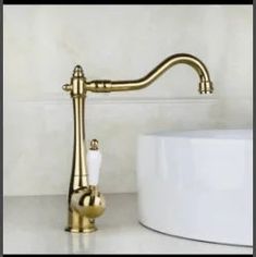 a gold faucet sitting on top of a white counter next to a sink