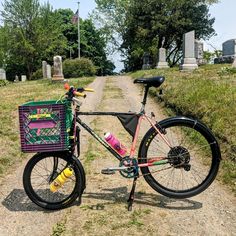 a bike parked on the side of a dirt road next to a cemetery with grass and trees