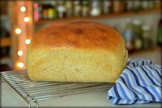 a loaf of bread sitting on top of a cooling rack next to a blue and white towel