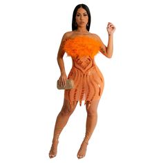 a woman in an orange dress with feathers on her chest and legs, posing for the camera