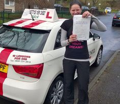 a woman standing next to a white car holding up a piece of paper in front of her