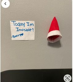 a santa hat is hanging on the wall next to a sign that says today i'm invisible