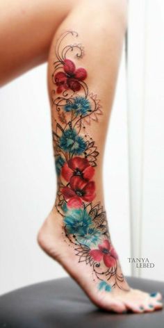 a woman's leg with flowers on it and an artistic tattoo design in the center