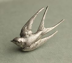 This great swallow brooch is a vintage metal stamping that has been treated to bring out the amazing details on the piece.  It is very high quality silver plated brass, with a silver plated brass brooch pin securely attached.   The bird brooch measures 48mm by 25mm at its widest points. 🖤 FASTER SHIPPING 🖤 Need this fast? We offer a Faster Shipping option here: https://www.etsy.com/uk/listing/100107311/faster-shipping-priority-post-upgrade Please read the description before purchasing this listing, as we are unable to post every day! Any questions, just ask. 🖤 GIFT MESSAGE & WRAP SERVICE! 🖤 For those of you who are sending gifts straight to your loved one, we are happy to offer beautifully designed gift wrapping and to include a personal message from you in the package, printed on a sw Swallow Earrings, Antique Bouquet, Brass Brooch, Silver Brooch Pin, Silk Purse, Swallow Bird, Bouquet Charms, Silver Bird, Winter Jewelry