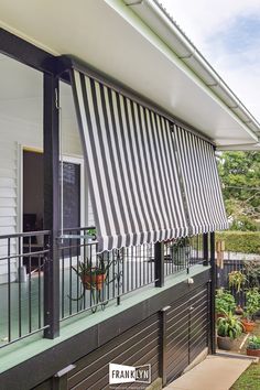 a black and white striped awning on the outside of a house with potted plants