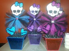 three pots with fake skulls in them on a table next to a wall and a cup