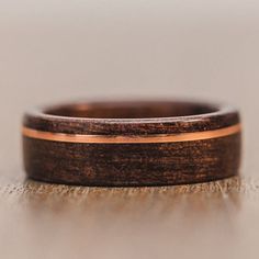 a wooden ring with gold inlays sits on a table, ready to be used as a wedding band