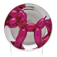 a pink balloon dog sitting on top of a glass plate in front of a white background