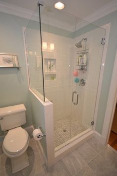 a white toilet sitting next to a shower in a bathroom on top of a tiled floor