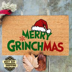 a door mat that says merry grinchmas next to leaves and acorns