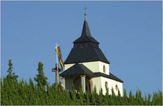 a white and black building with a steeple on it's side surrounded by trees