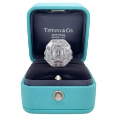 an octagonal cut diamond ring in a blue box with the lid open to show it's inside