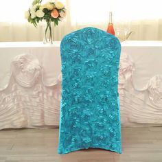 a blue chair cover sitting on top of a wooden floor next to a vase filled with flowers