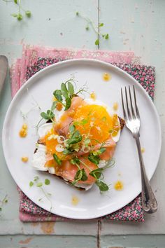 a white plate topped with food on top of a pink and green place mat next to a fork