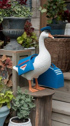 a duck statue sitting on top of a piece of wood next to potted plants