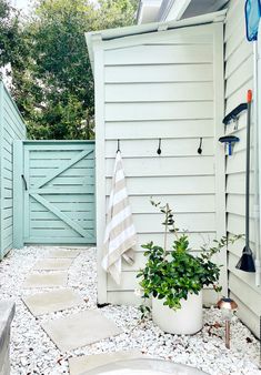 an outdoor shower with a towel and potted plant