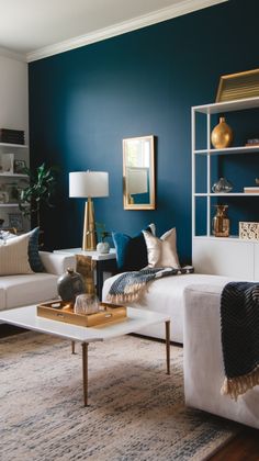 a living room with blue walls and white couches, gold accents on the coffee table