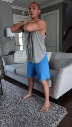 a man standing in front of a couch with his arm stretched out to the side