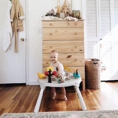 a baby sitting in a highchair with toys on it's back legs