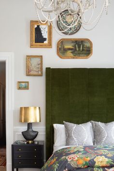 a green headboard in a bedroom with pictures on the wall and chandelier above it