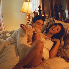 a man and woman laying in bed laughing