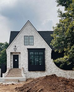 a white brick house with black shutters on the front door and steps leading up to it