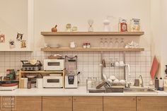 a kitchen with lots of clutter on the counter top and shelves above it that are filled with dishes