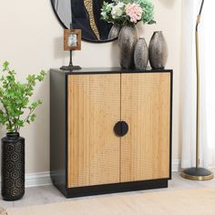 a wooden cabinet with two vases and a mirror on the wall