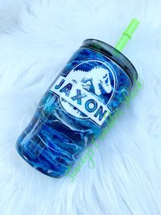 a blue and green cup sitting on top of a white fur covered floor next to a neon green straw