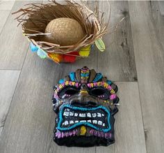 a decorative mask sitting on the floor next to a basket