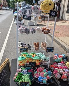 there are many different items on display at this street vendor's stand, including knitted shoes and crochet hats