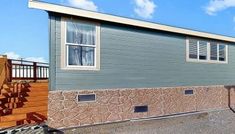 a mobile home with stairs leading up to the front door and side porch, on a sunny day