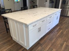 a large kitchen island with white cabinets and marble counter tops