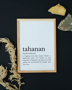 there is a frame with the word tahanan on it next to some dried plants