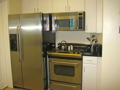 a metallic refrigerator freezer sitting next to a stove top oven in a small kitchen