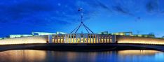 the parliament building lit up at night with lights reflecting off water and clouds in the sky