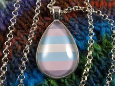 The Demiboy Pride flag has a sequence of stripes going from dark grey, light grey, light blue, white, light blue, light grey, to dark grey. This necklace features the Demiboy Pride flag, set into a silver-tone drop-shaped 20x30mm pendant, and covered by a domed glass cabochon. The pendant is hung from a 24'' silver tone rolo chain.  Wear this necklace with pride! The necklace is water resistant but not completely waterproof, not recommended to wear in water. **Spacerobot Studio donates 10% of sales to charity.** Pendant Necklace Silver, Grey Light, Pride Flag, Rolo Chain, Pride Flags, Necklace Silver, Blue Light, Silver Necklaces, White Light