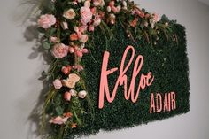 a sign that says khloe adair with flowers and greenery on it