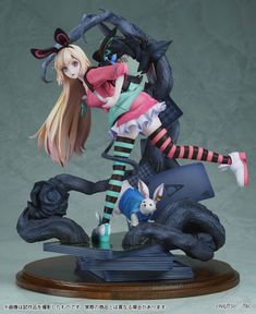 an anime figurine is posed on top of a wooden base with a cat