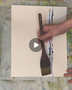 a person holding a brush on top of a piece of paper