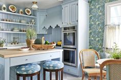 a kitchen with two stools in front of an island and shelves on the wall