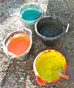 three buckets filled with different colored paint sitting on the ground