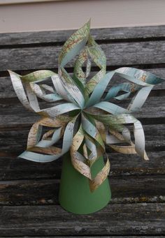 a green vase filled with lots of different types of paper and tape on top of a wooden bench