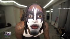 a man with his face painted white and black, standing in an office hallway looking at the camera