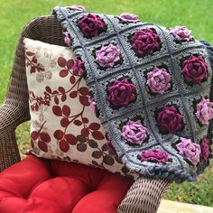 two crocheted pillows sitting on top of a wicker chair