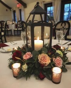 the centerpiece is adorned with roses and greenery, while candles are lit on the table