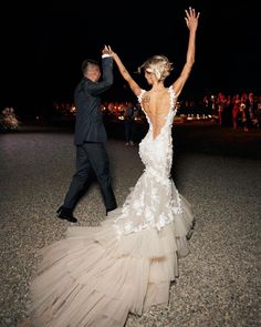 a bride and groom dancing in the street at night with their hands up to each other