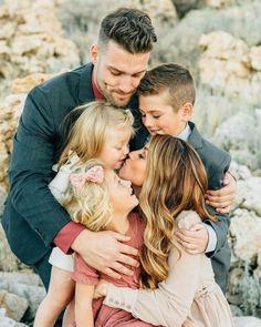 a man and two children hugging each other while standing in front of some rocks with their arms around them