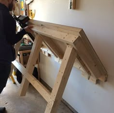 a man standing next to a wooden table in a room filled with tools and supplies